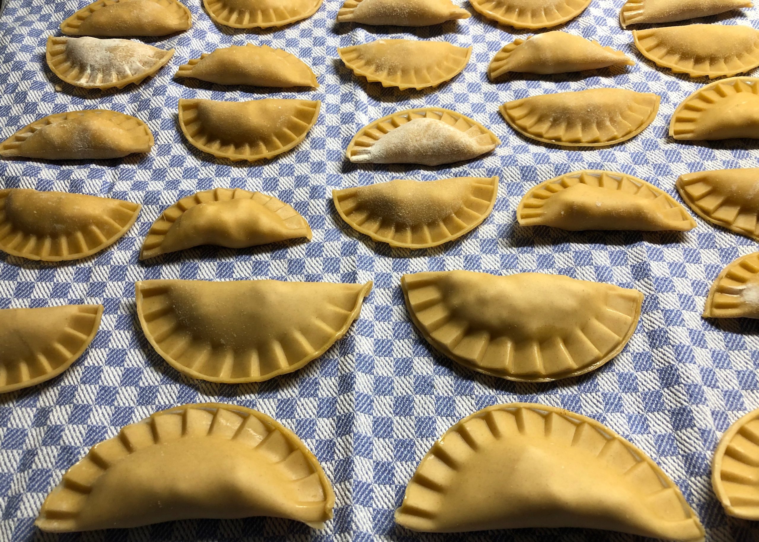 Auf einem Kuchentuch liegen nebeneinander ungekochte Ravioli zum Trocknen Ich feiere die Pasta am World Pasta Day