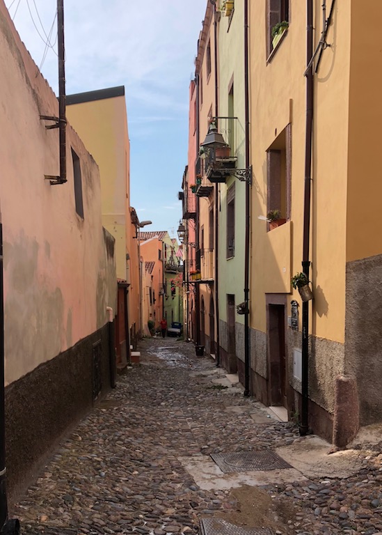 Die für Bosa so typischen gepflasterte schmale Gasse. Am rechten Bildrand kolorierte Häuser.