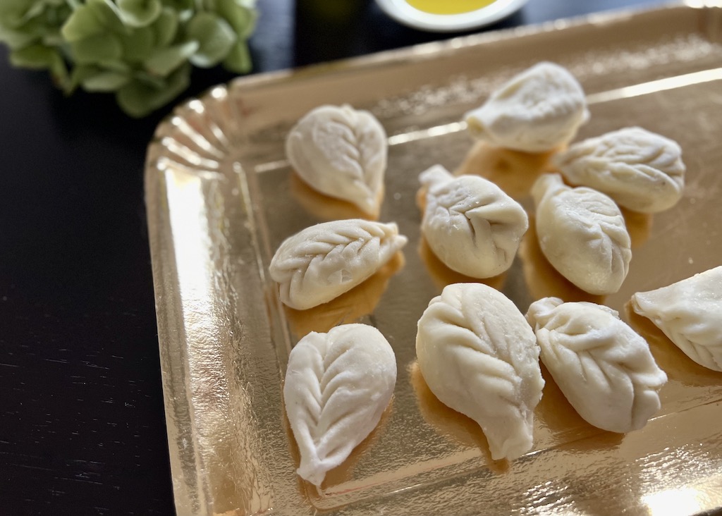 Sardische Pasta Culrurgiones Auf einem goldfarben Papptablett liegen mehrere Culurgiones.