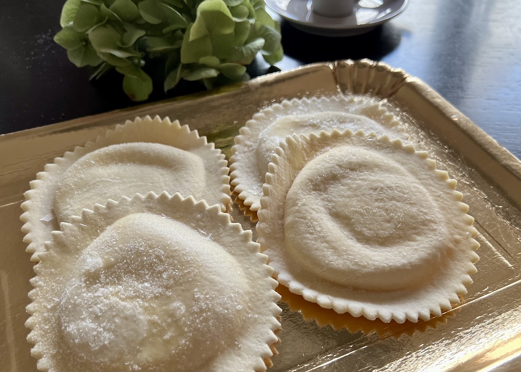 Seadas oder Sebadas Mitbringsel von Sardinien: Vier Seadas oder Sebadas auf einem goldfarbenen Papptablett