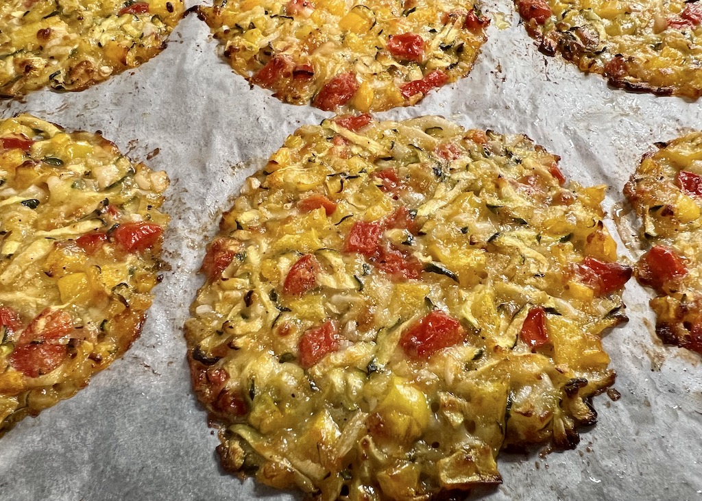 S'anguli 'e cipudda - die sardische Pizza. Gebackene handflächengroße S'anguli 'e cipudda liegen nebeneinander auf einem mit Backpapier ausgelegten Backblech 